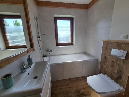 a bathroom with a tub and a sink and a toilet at NowiNowe Domki in Dzianisz