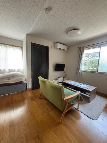 ein Wohnzimmer mit einer grünen Couch und einem Bett in der Unterkunft Little House Private House in Yakushima