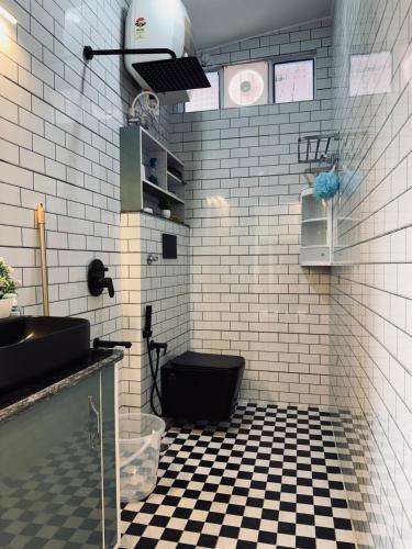 a bathroom with a black toilet and black and white tiles at The Second Home , Chamba Hills in Chamba