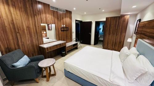 a bedroom with a bed and a chair and a sink at Sidra Serviced Apartments - سدرا للشقق المخدومة in Al Khobar