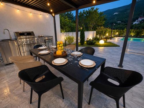a dining table and chairs with a kitchen and a table and chairs at Villa Perla di Draga in Mošćenička Draga