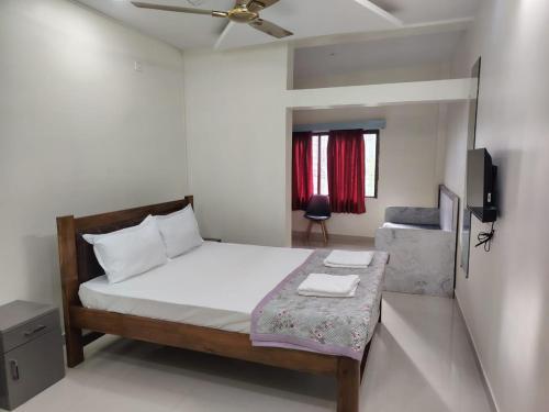 a small bedroom with a bed and a tv at Bliss Paradise Resort in Malvan