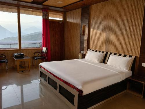a bedroom with a large bed with a large window at Sherjang Events in Munsyari