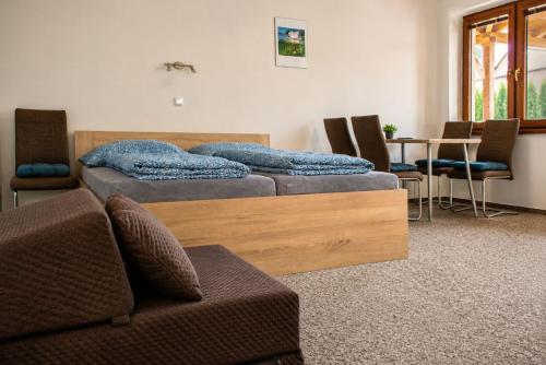 two beds in a room with a couch and a table at Penzion U Kyjovky, Týnec in Týnec