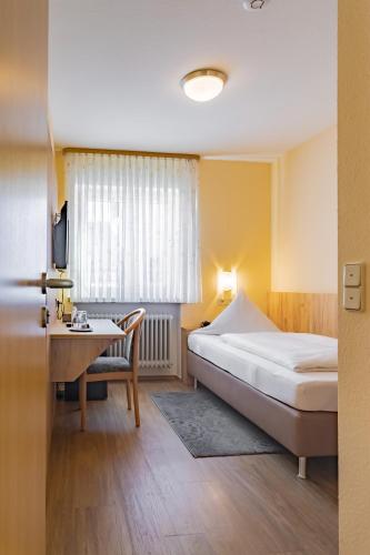 a bedroom with a bed and a desk with a computer at Hotel Garni WEISSES LAMM in Erlangen
