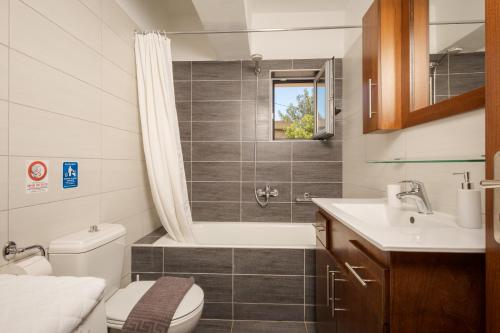 a bathroom with a tub and a toilet and a sink at Villa Maragoudi in Arménoi
