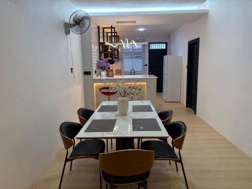 a dining room with a table and chairs and a kitchen at Permai Lake Residence in Sibu