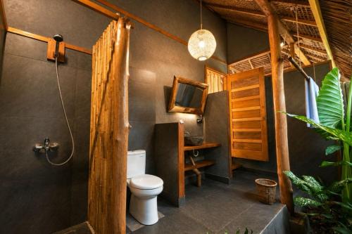 a bathroom with a toilet and a tv on the wall at Akar Mentawai in Simpatdegat