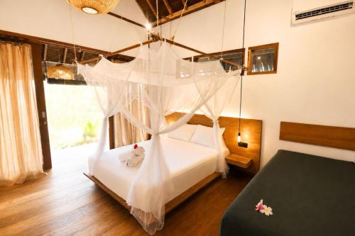 a bedroom with a bed with a mosquito net at Akar Mentawai in Simpatdegat