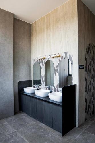 a bathroom with two sinks and two mirrors at Hotel Serenova, Pune- Pure Veg in Pune