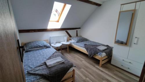 two beds in a room with a window and a mirror at Damianówka in Paczkówek