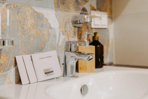 a bathroom sink with a faucet and a bottle of wine at Ferienwohnungen Proschahaus in Eisenberg an der Pinka