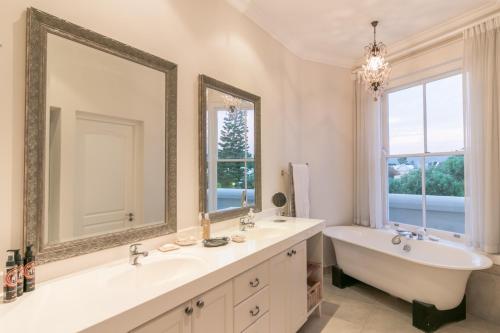 a bathroom with a tub and a sink and a tub and a mirror at Isola Bella Guest House in Knysna