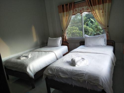two beds in a room with a window at Beyond Pub guest House and Hotel in Ban Tayun