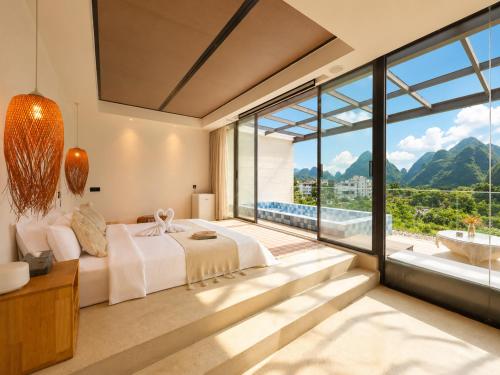 a bedroom with a bed and a large window at Yulong River Scenic Area,Floor-to-ceiling Windows for viewing,Swimming Pool & Coffee & Butler Service,10 minutes by car from West Street in Yangshuo