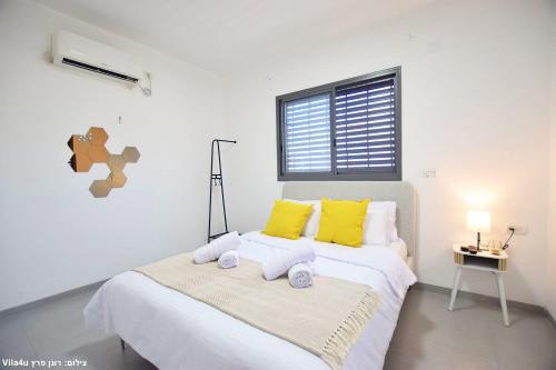 a bedroom with a bed with yellow pillows and a window at וילה מושלמת עם בריכה מפנקת וממ"ד בשכונת טבריה המושבה בעיר טבריה in Tiberias