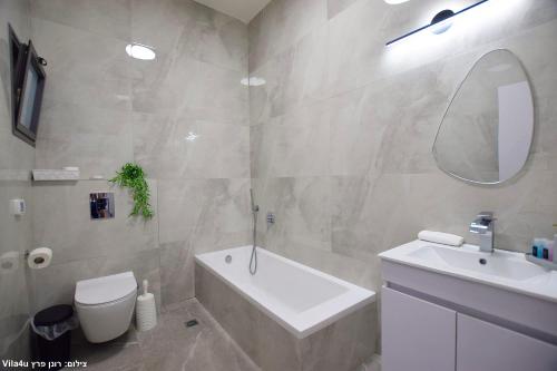 a bathroom with a sink and a tub and a toilet at וילה מושלמת עם בריכה מפנקת וממ"ד בשכונת טבריה המושבה בעיר טבריה in Tiberias