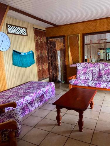 a living room with purple beds and a table at Maupiti Authentique in Te-Fare-Arii