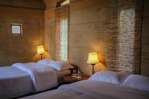 two beds in a room with two lamps and a table at Tiger Track Eco Lodge in Bardiyā