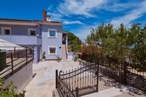 a villa with a gate and a house at Apartmani Raić in Mali Lošinj
