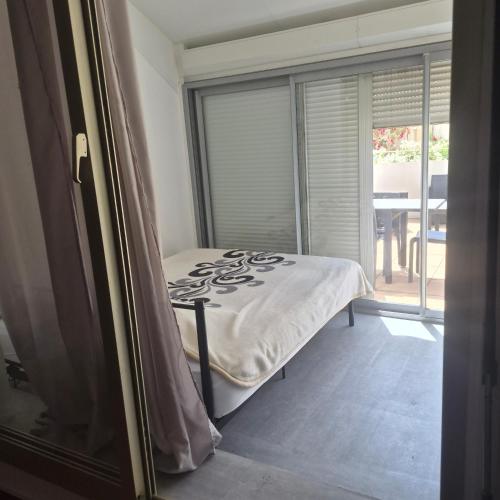 a bedroom with a bed and a large window at Studio avec grande terrasse in Carnon-Plage