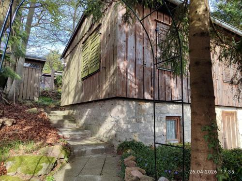 a building with a tree next to a sidewalk at Emma's Vintage Ferienhaus mit Kamin in Friedrichsbrunn
