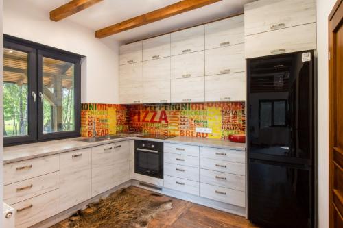 a kitchen with white cabinets and a black refrigerator at Łowisko Dom ze Stawami in Trudna