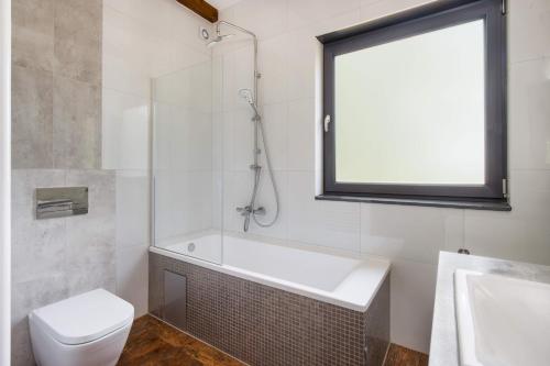 a bathroom with a tub and a toilet and a window at Łowisko Dom ze Stawami in Trudna
