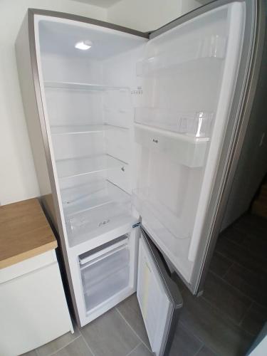 an empty refrigerator with its door open in a kitchen at Loft cosy 4 in city center in Saint-Benoît-sur-Loire