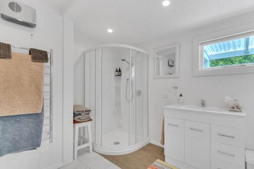 a white bathroom with a shower and a sink at Rose Cottage - Tranquil retreat in Tinui