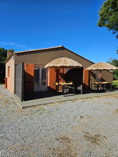 un petit bâtiment avec deux tables et des parasols dans l'établissement Menthe, à Challans