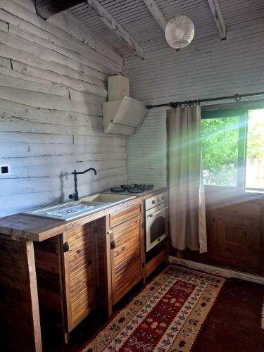 a kitchen with a stove and a sink and a window at Tahtavilla Pansiyon in Cıralı