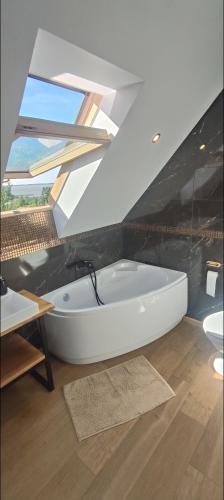 a white bath tub in a bathroom with a window at Agrodomki Okej - Dom Oleńka in Gardna Wielka