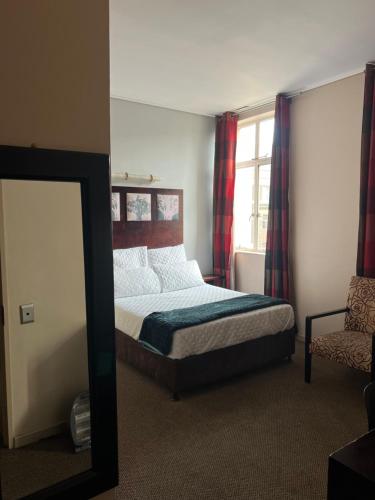a bedroom with a bed and a mirror and a chair at Warm & Cozy Diamonds Hotel in Johannesburg