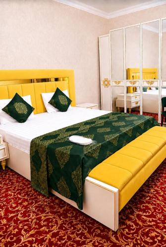 a bedroom with a large bed with a green and yellow blanket at Sultanahmet Hotel in Baku