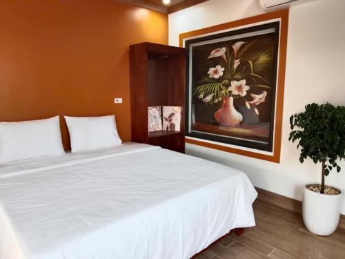 a bedroom with a white bed and a painting at Rice Fields Mountain Homestay in Vũ Lâm