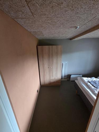 a room with a bed and a wooden cabinet at Lofoten Apartment 02 in Leknes