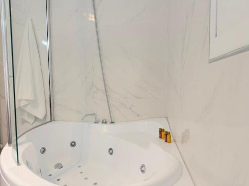a bathroom with a white tub and a sink at Ugo Jacuzzi Apartment in Bologna