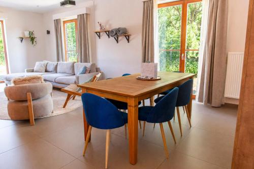 a living room with a wooden table and blue chairs at Les jardins du Quesnoy - 25min de Pairi Daiza in Blicquy
