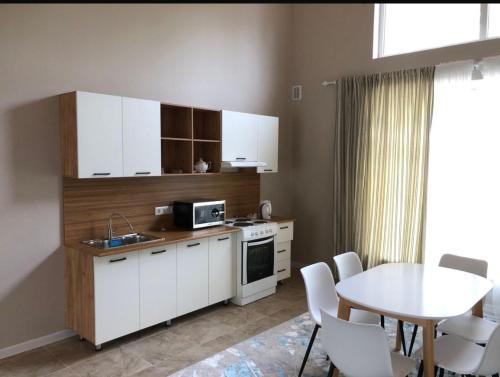 a kitchen with white cabinets and a table and a table and chairs at Дом у Айбека in Tamga