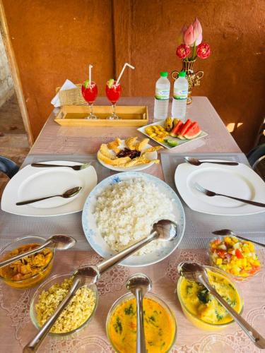 a table topped with plates and bowls of food at Nature Nest Cabana in Sigiriya