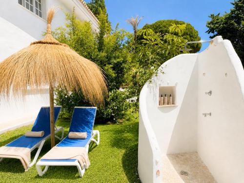 a couple of chairs and an umbrella on the grass at Aurora Boutique - Only Adults in Marbella