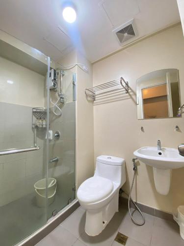 a bathroom with a toilet and a shower and a sink at 1008 T2 Avida Tower Atria Comfy Cozy in Iloilo City