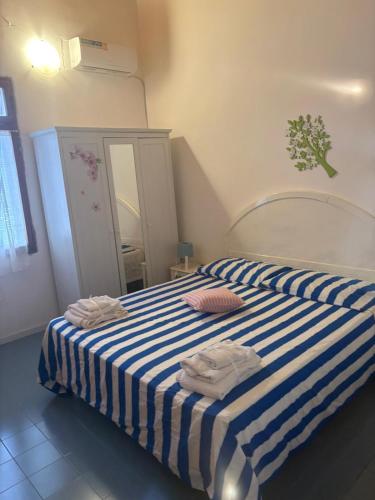a bedroom with a striped bed with two towels on it at Villetta Darsena con piscina gratuita dal 18 Luglio al 30 Agosto in Vulcano