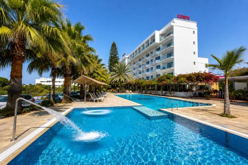 a swimming pool with a fountain in front of a hotel at Corfu Hotel in Ayia Napa