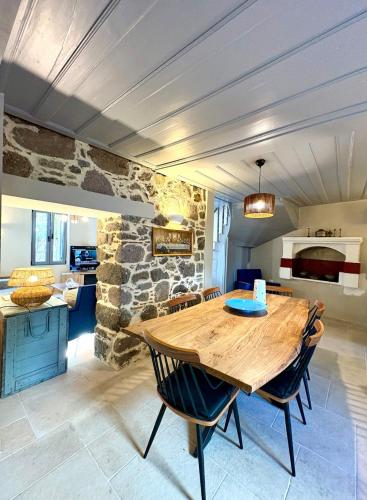 a dining room with a wooden table and a stone wall at The Prοfessοrs House - Myrina 1922 in Myrina