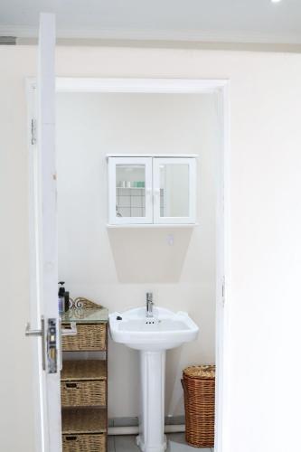 a white bathroom with a sink and a mirror at 12 On York Guesthouse in Bloemfontein