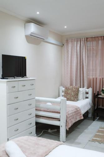 a bedroom with a bed and a dresser with a tv at 12 On York Guesthouse in Bloemfontein