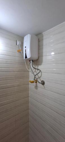 a bathroom with a white tiled wall with a water heater at Umbrella Guest House - Palace Suite in Madurai