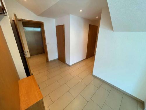 an empty room with a hallway with doors and a tile floor at Allegra am Niederrhein in Neukirchen-Vluyn